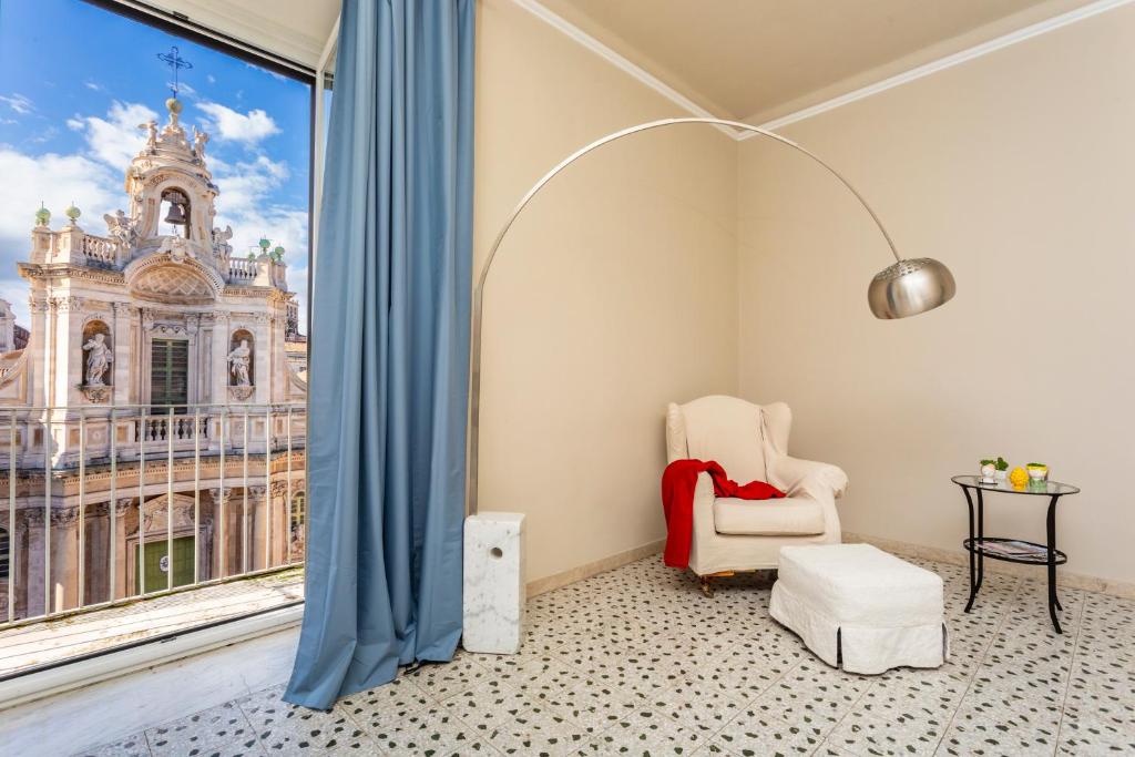 Angolo lettura con poltrona bianca e lampada ad arco accanto alla portafinestra aperta sulla facciata barocca della Basilica della Collegiata