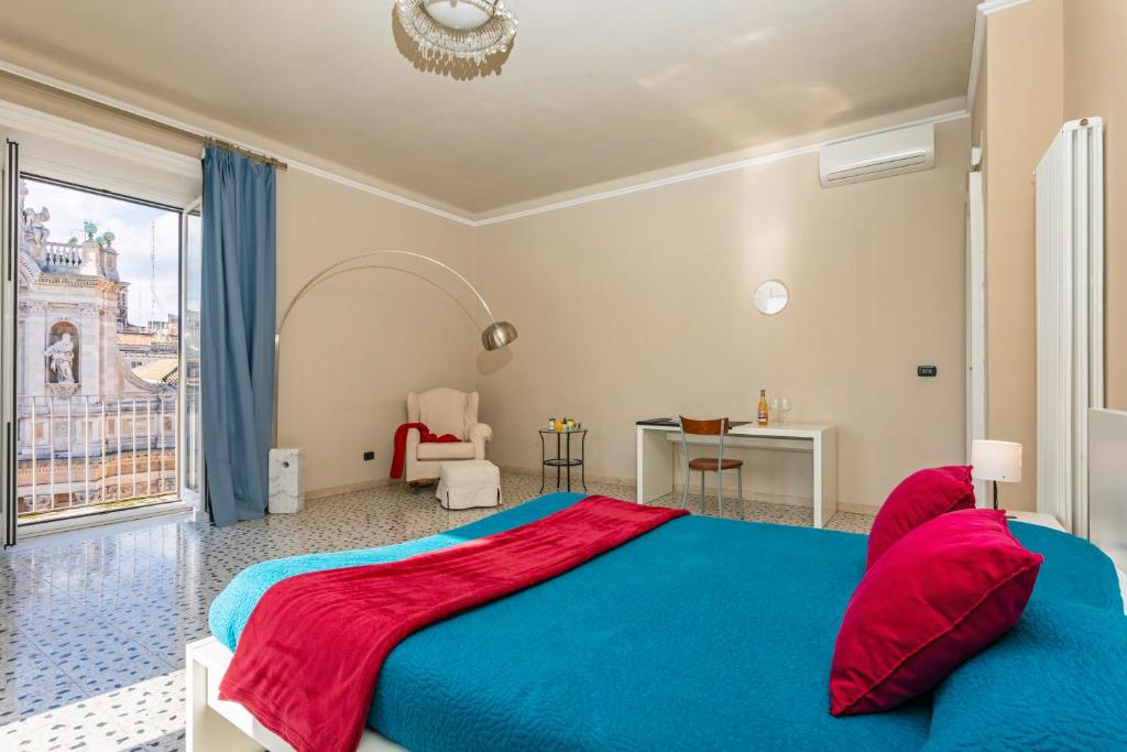 Großes Schlafzimmer mit Terrazzoboden, türkisfarbener Tagesdecke und Fenstertür zum Balkon mit Blick auf die Collegiata