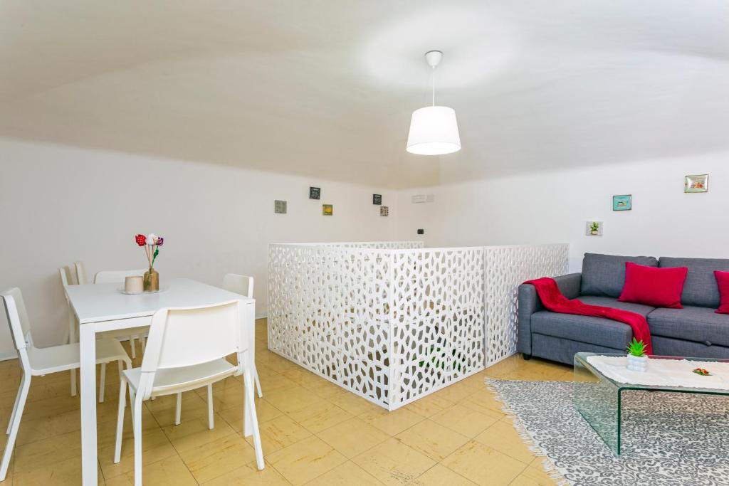 Wohnzimmer mit Gewölbedecke, weißem Esstisch, grauem Sofa mit roten Kissen und durchbrochenem Paravent