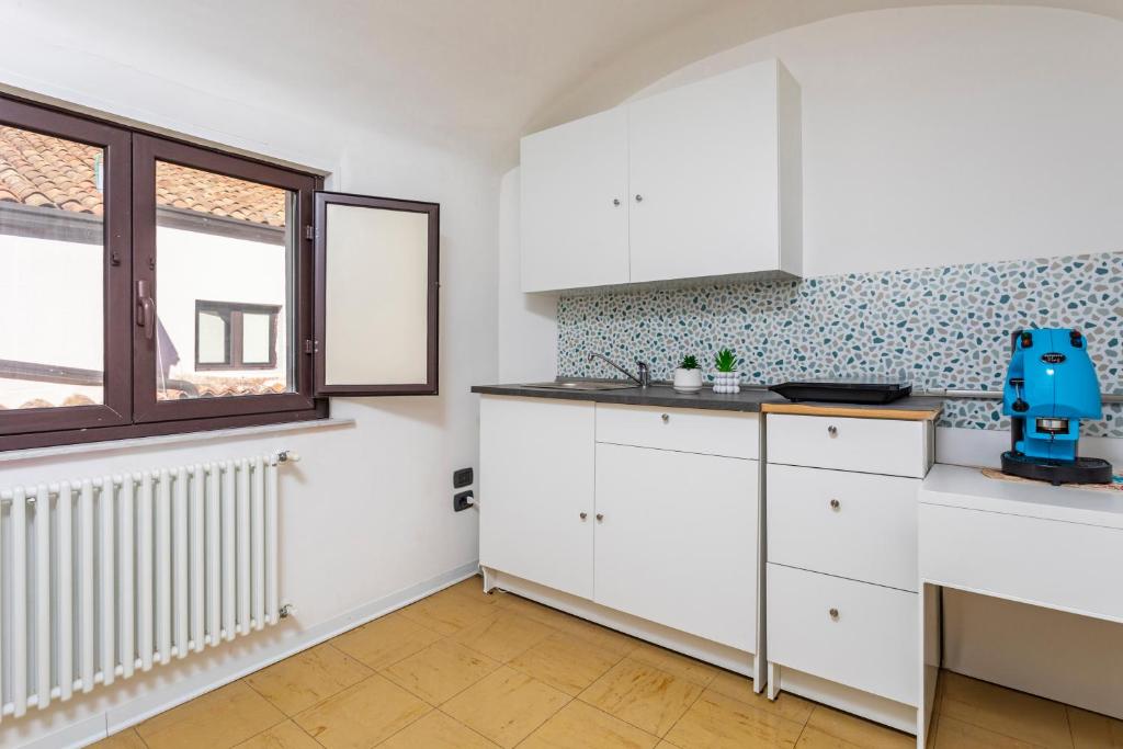 Weiße Küche mit Kochfeld, Spüle, Kaffeemaschine und Fenster über den Dächern